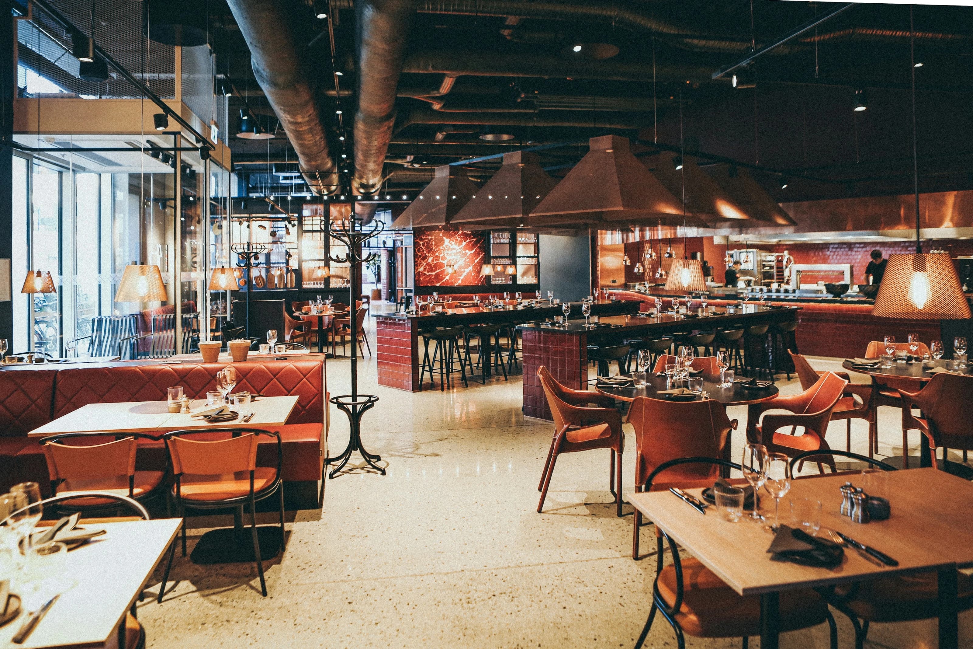 A contemporary dining room with leather seating, laid tables and warm lighting